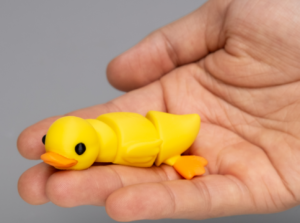 Hand holding a small yellow toy duck.