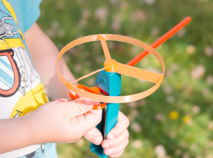 Child holding a toy flying spinner outdoors.