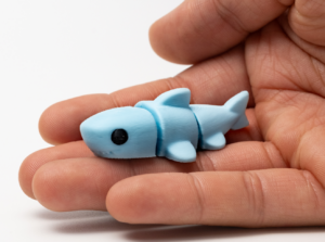 Hand holding a small blue shark figurine.